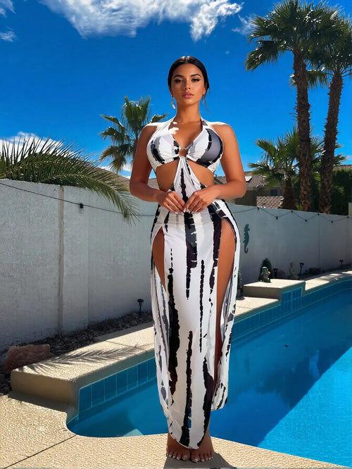 Woman in black and white abstract print cutout maxi dress standing by a swimming pool.