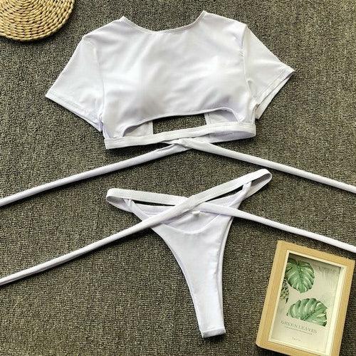 Two-piece white bikini set with a short sleeve crop top and side-tie bikini bottoms.