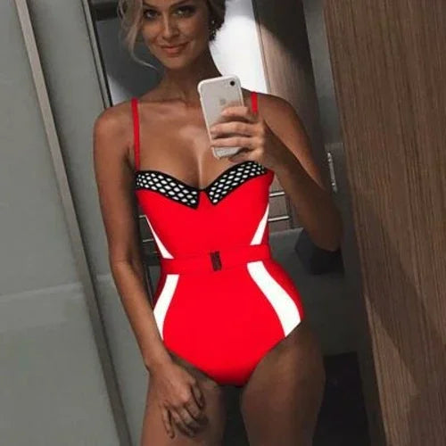 Woman in a red one-piece swimsuit with black mesh trim and a belted waist