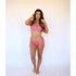 Woman wearing a neon pink triangle bikini set with side-tie bottoms against a white background