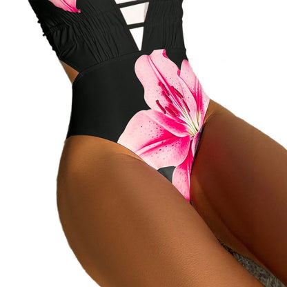Woman wearing a black one-piece swimsuit featuring a large pink lily floral print.