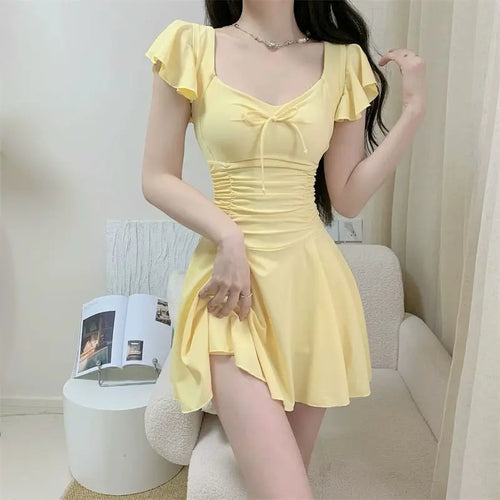 Woman wearing a pale yellow ruffled one-piece swimsuit with a sweetheart neckline.