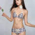 Woman wearing a plaid print two-piece bikini set with a white flower choker.