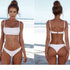 Woman wearing a white two-piece bikini set standing on a sandy beach.