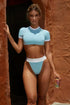 Woman wearing a light blue crop top and matching high-waisted bikini bottoms.